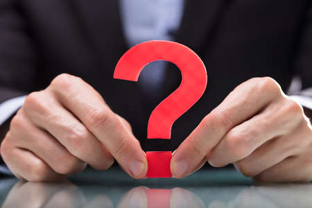 Close-up Of A Businessperson's Hand Holding Red Question Mark Signの写真素材