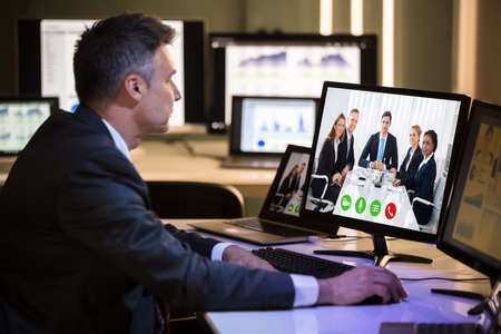 Side View Of A Businessman Video Conferencing With Happy Colleagues On Computer In Officeの写真素材