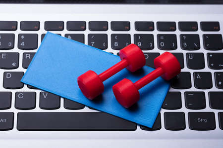 Elevated View Of Dumbbells And Exercise Mat On Computer Keyboardの写真素材