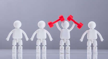 Human Figures Standing In A Row Exercising With Red Dumbbells Against Grey Backgroundの写真素材