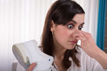 Close-up Of A Young Woman Holding Stinky Shoe