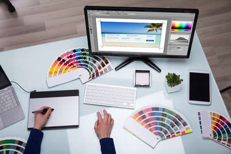 Elevated View Of Designer's Hand Using Graphic Tablet Working On Computer