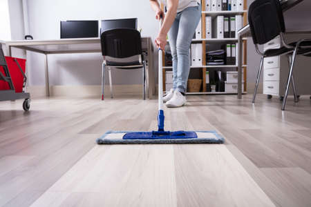 Janitor's Hand Cleaning Floor With Mop At Workplace