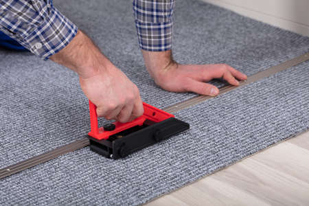 Close-up Of A Male Carpet's Hand Fitter Installing Carpet With Tool