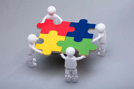 High Angle View Of Human Figures Solving Multi Colored Jigsaw Puzzles