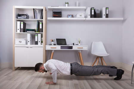 Young Businessman Doing Push Up At His Workplace