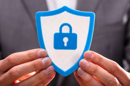 Close-up Of A Businessperson's Hand Holding Blue Shield Security Iconの写真素材