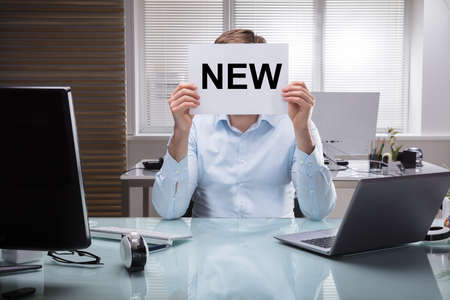 Businessman Holding Placard With New Text In Front Of His Faceの写真素材