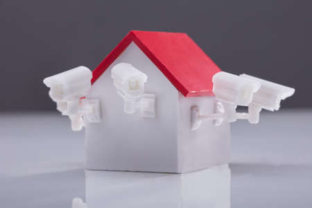 Close-up Of House Model With Surveillance Camera On Reflective Backgroundの写真素材