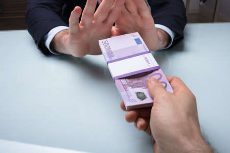 Close-up Of A Businessman's Hand Refusing Bribe Offered By His Partnerの写真素材