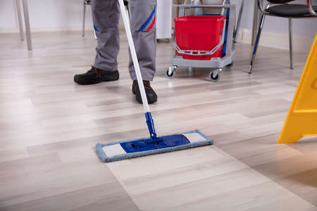 Cleaner Cleaning Hardwood Floor With Mop At Workplace