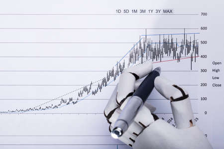 Elevated View Of A Robotic Hand Holding Pen Over Financial Documentの写真素材
