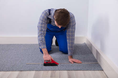Close-up Of A Carpet Fitter's Hand Installing Grey Carpet With Wireless Screwdriverの写真素材