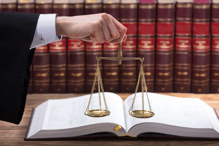 Judge Holding Justice Scale In Front Of Law Book