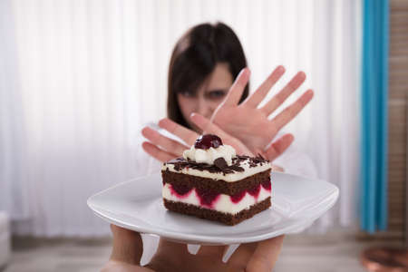 Woman Refusing Slice Of Delicious Cake Offered By A Personの写真素材