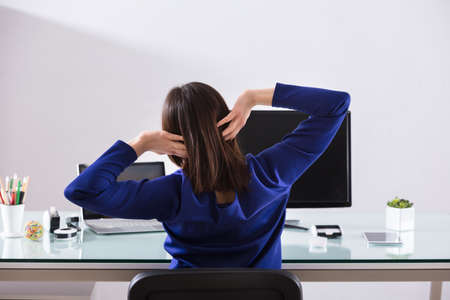 Close-up Of A Young Businesswoman Stretching Her Arms At Workplaceの写真素材