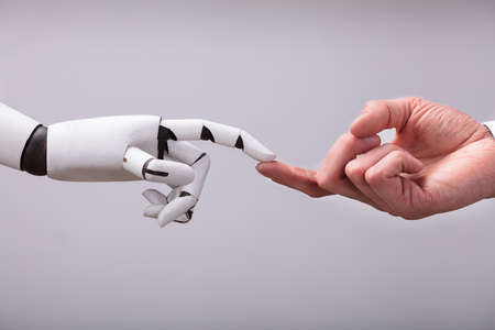 Robot Touching Human Finger Against Gray Backgroundの写真素材