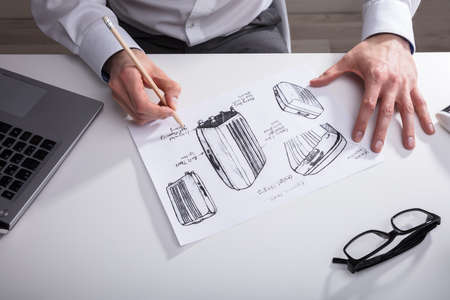 Close-up Of An Artist's Hand Sketching On Paper With Pen Over Desk