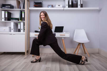 Side View Of A Happy Businesswoman Doing Stretching Exercise In Office