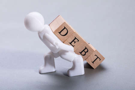 White Human Figurine Carrying Debt Wooden Blocks On Grey Backgroundの写真素材