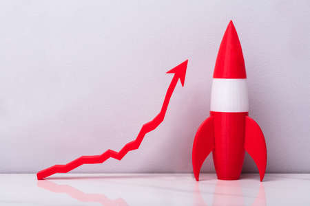 Red Rocket Near White Increasing Arrow Graph On Grey Backgroundの写真素材