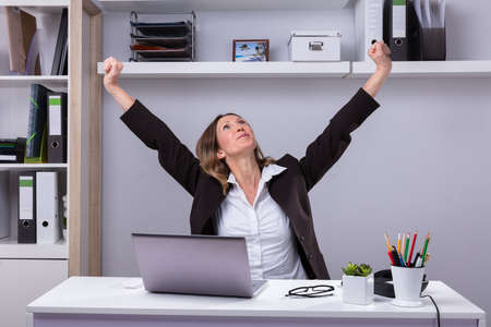 Mature Businesswoman Stretching Her Arms At Workplace