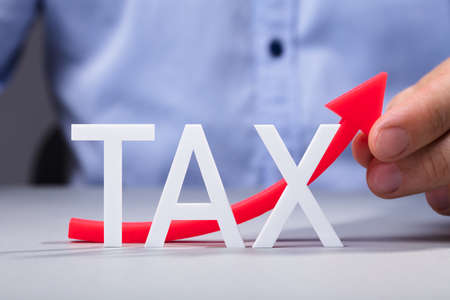 Red Increasing Arrow Behind The White Tax Word On Reflective Deskの写真素材