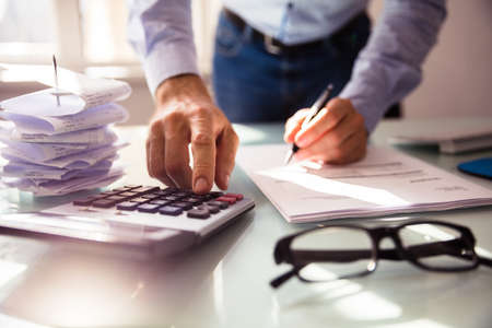 Close-up Of A Businessperson's Hand Using Calculator In Officeの写真素材