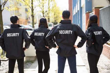 Rear View Of Security Guards With Hands Behind Back Standing In A Rowの写真素材