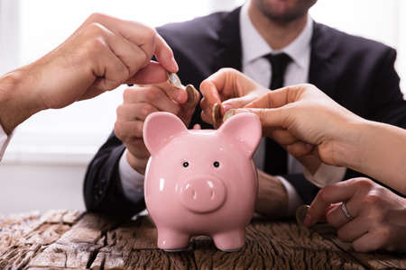 Crowdfunding Concept. People Inserting coins into piggybankの写真素材
