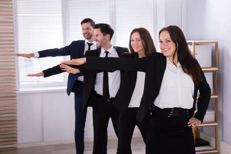 Happy Businesspeople Standing In A Row Doing Exercise With Hands Outstretchedの写真素材