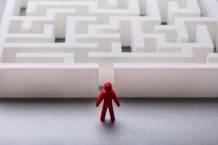 Close-up Of Red Human Figure Standing Outside Maze Entrance