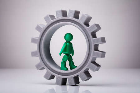 Green Human Figure Walking On Gray Gear On White Backgroundの写真素材