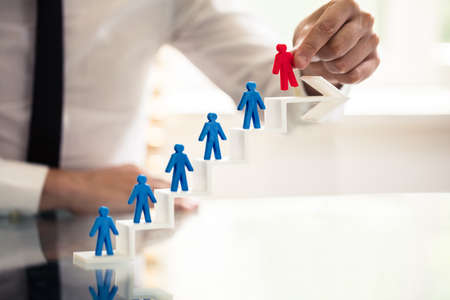 Businessperson Picking Red Human Figure From Staircase Made Of Arrowの写真素材