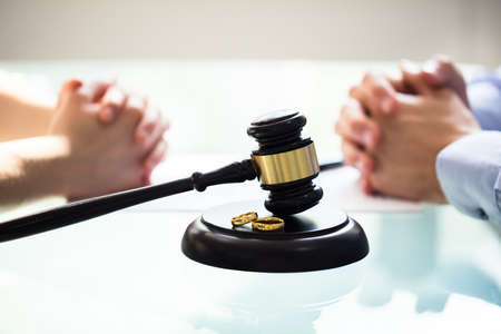 Close-up Of Gavel And Wedding Rings In Front Of Couple's Handの写真素材