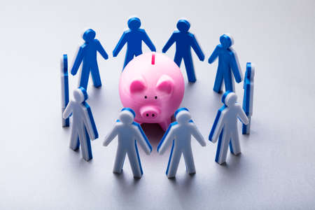 Elevated View Of Human Figures Surrounding Pink Piggybank On White Background
