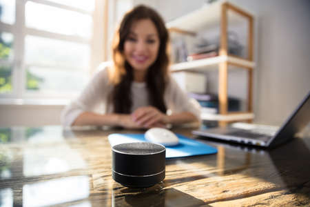 Close-up Of Wireless Speaker In Front Of Businesswoman Listening To Musicの写真素材