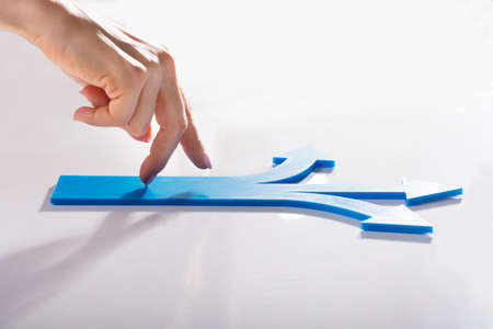 Woman's Finger Walking On Blue Arrows Showing Various Directionsの写真素材