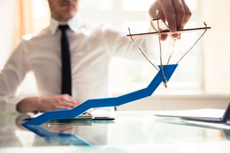 Businessperson's Hand Manipulating Blue Arrow With Ropeの写真素材