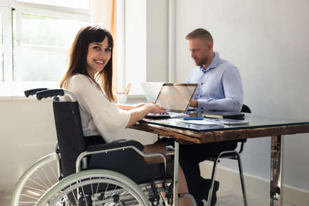 Happy Disabled Businesswoman Working On Laptop With Her Partner
