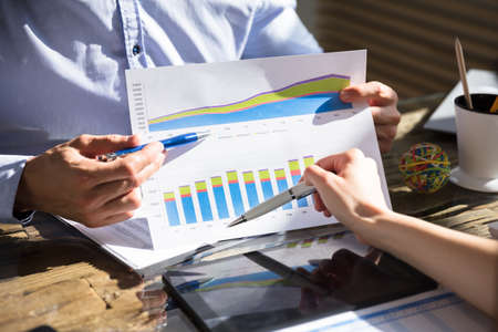 Young Businessman Analyzing Graph With His Partner At Workplace