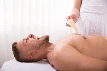 Close-up Of Beautician's Hand Waxing Man's Chest In Spaの写真素材