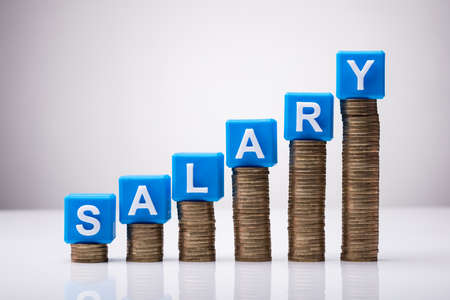 Blue Salary Cubic Blocks On Increasing Stacked Coins Against White Backgroundの写真素材