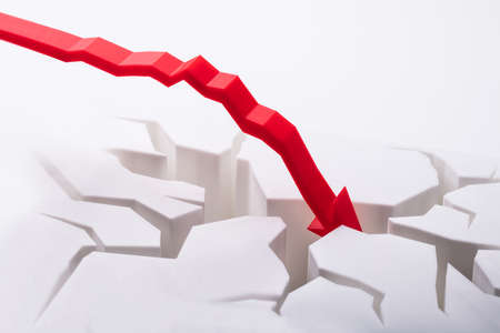 Close-up Of Falling Red Arrow Breaking White Surfaceの写真素材