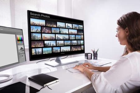 Young Female Editor Searching Photos On Computer At Workplaceの写真素材