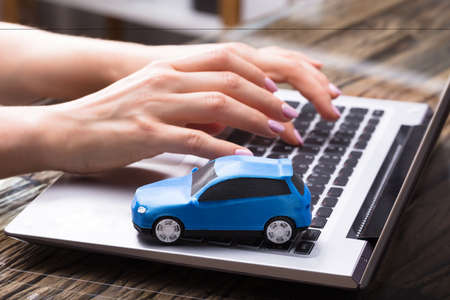 Businesswoman Working On Laptop With Small Blue Carの写真素材