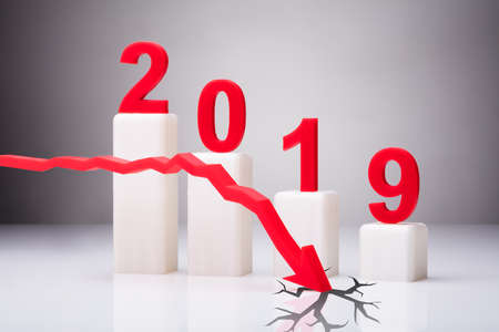 Red Arrow Cracking White Surface In Front Of Decreasing Year 2019 Graph