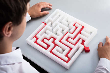 Elevated view of businessman solving maze on deskの写真素材