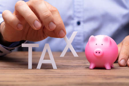 Human Hand Picking S Alphabet From Tax Word Beside Piggybankの写真素材