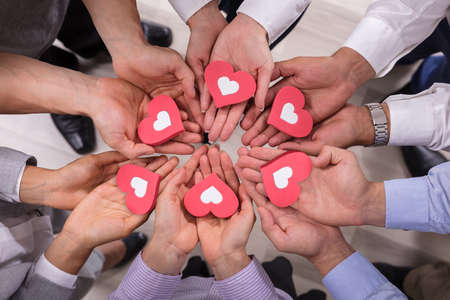 High Angle View Of Businesspeople Holding Red Hearts